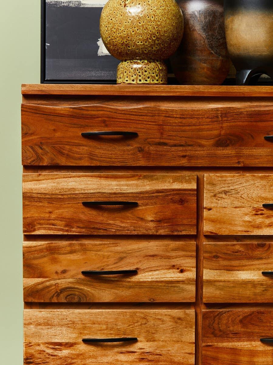 Solid wood chest of drawers with black handles and decorative vases on top