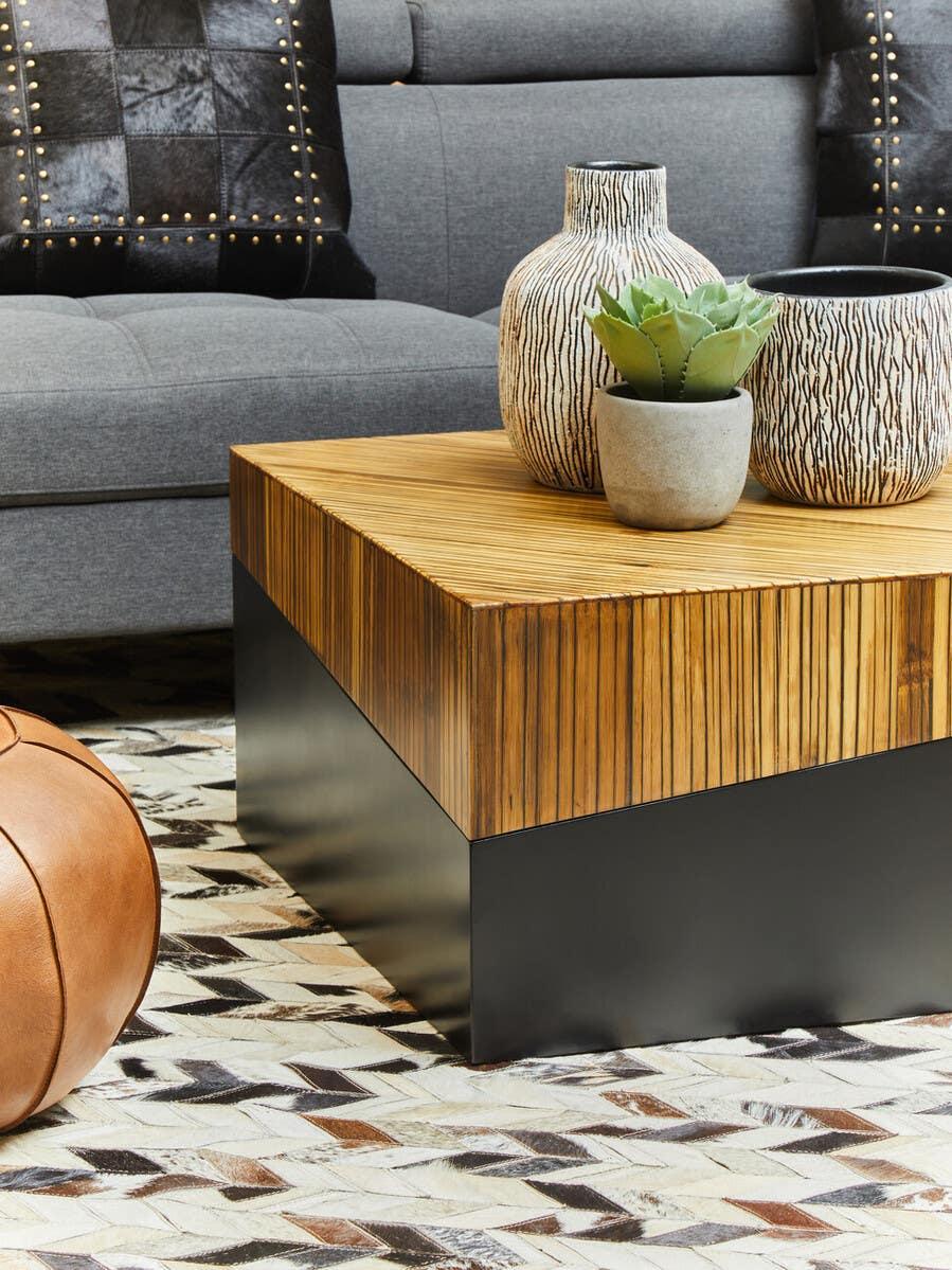 Square wood coffee table with black base, vases, and plant decor in modern living room