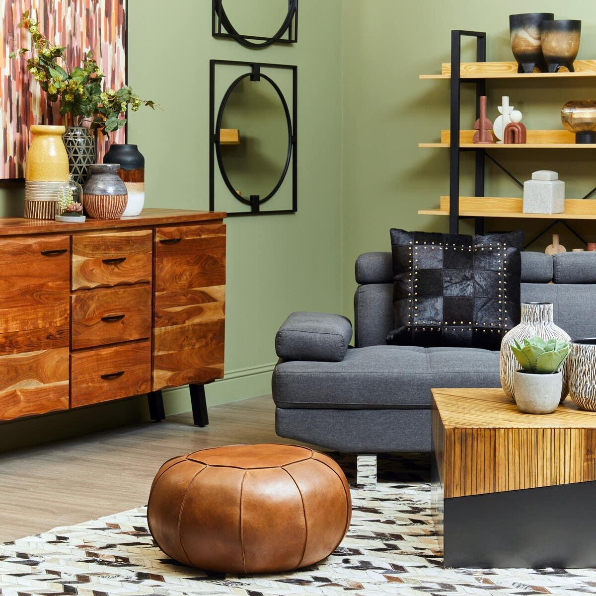 Modern living room with grey sofa, leather pouffe, wooden sideboard and shelving