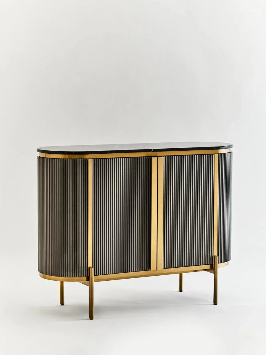 Black and gold sideboard cabinet with ribbed doors and curved edges on gold legs