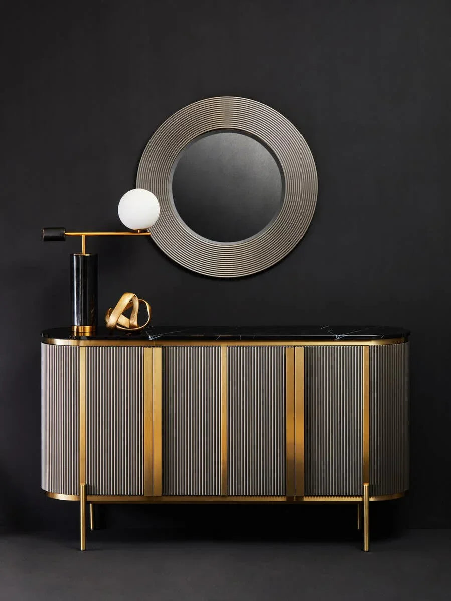 Modern sideboard with gold accents, black marble top, and round wall mirror on dark background