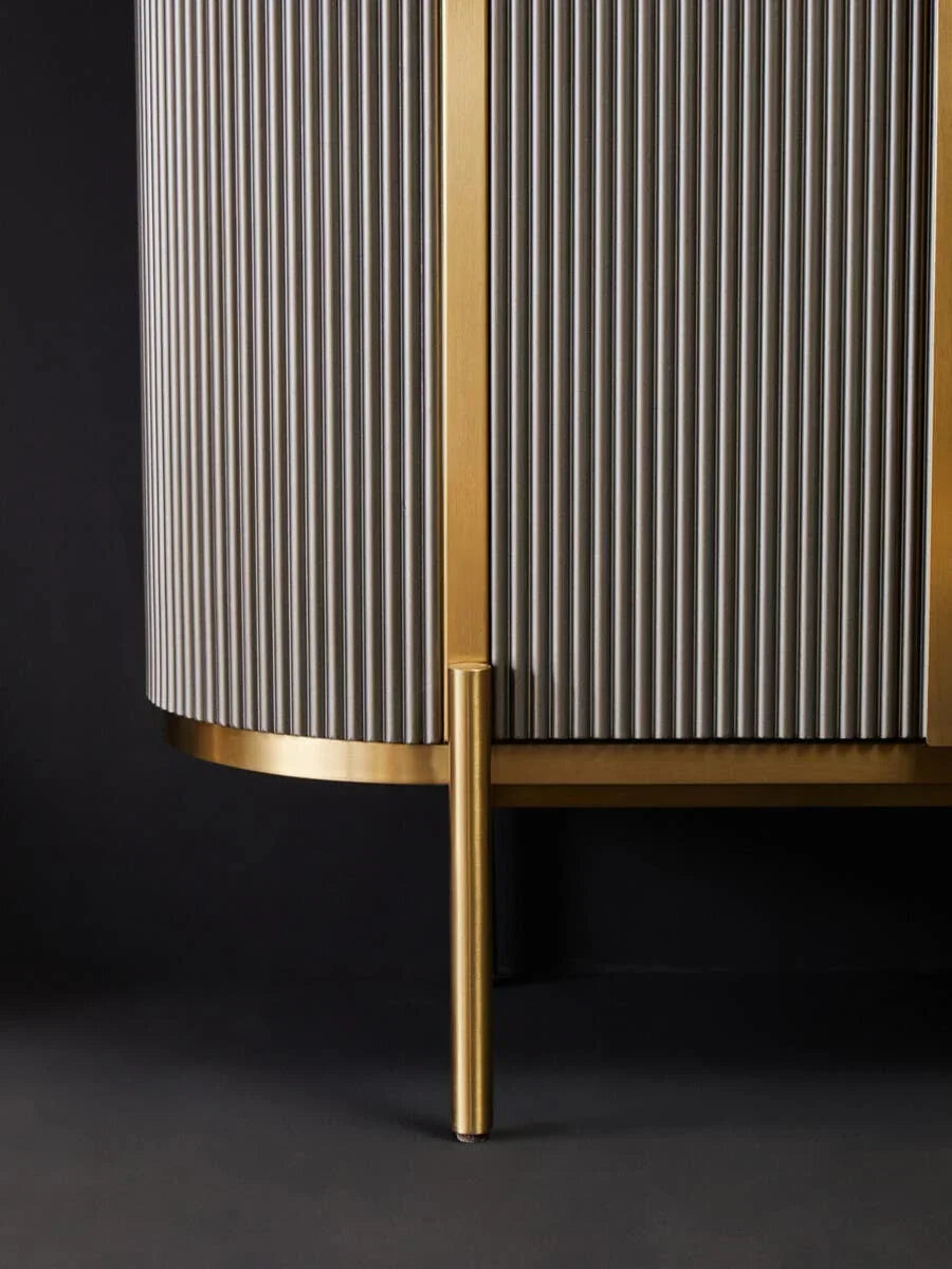 Close up of modern gold and grey cabinet with ribbed doors and metal leg