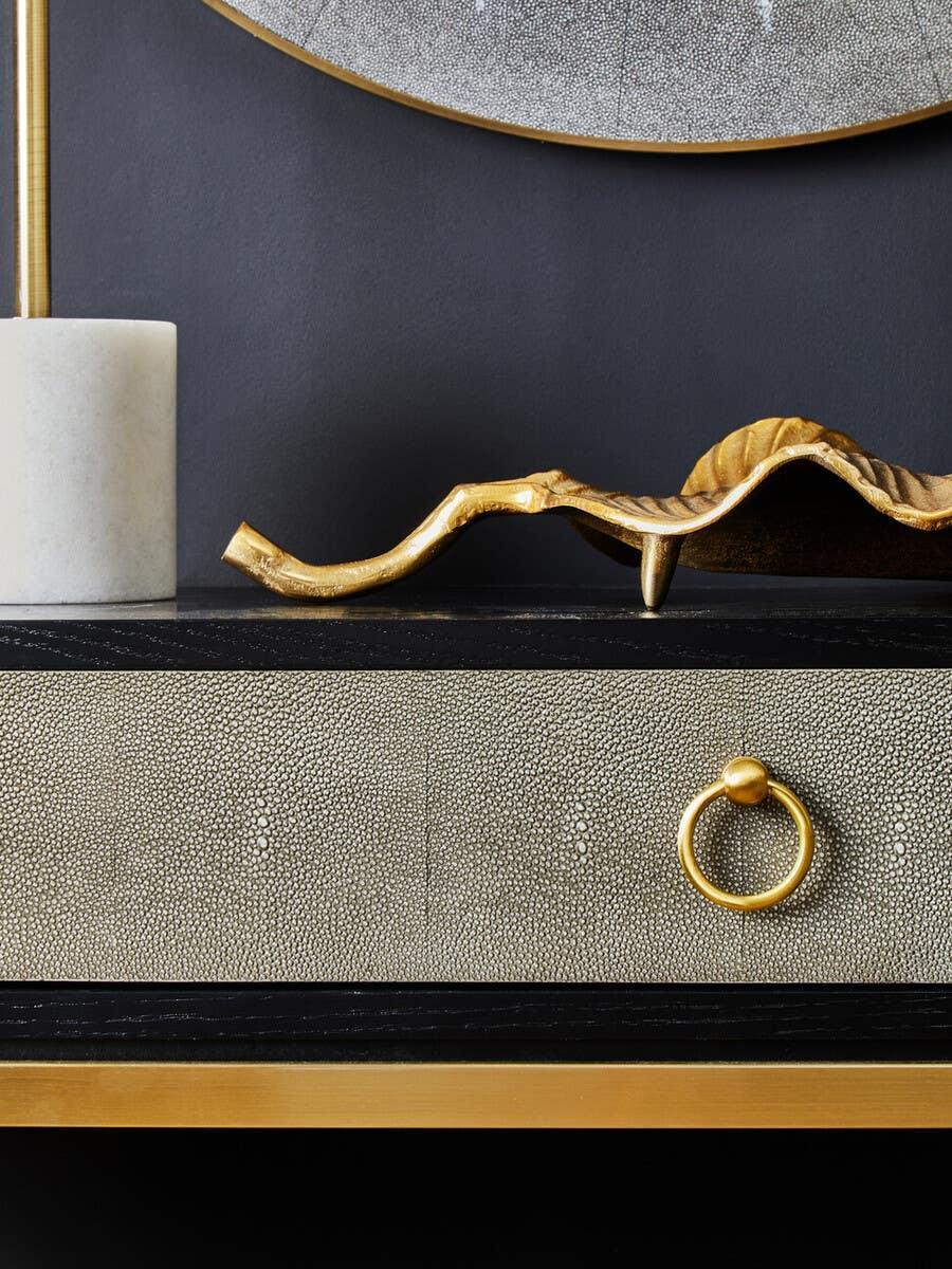 Textured drawer with gold handle and decorative tray on a black and gold console table