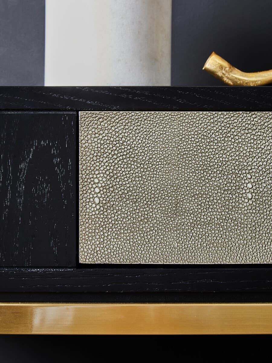 Black wood sideboard with textured drawer front and gold base detail
