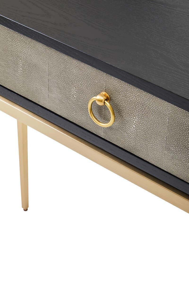 Close-up of modern console table with black top, textured drawer, and gold metal handle