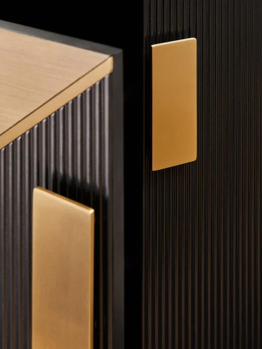 Black cabinet with gold metal handles and ribbed panel detail