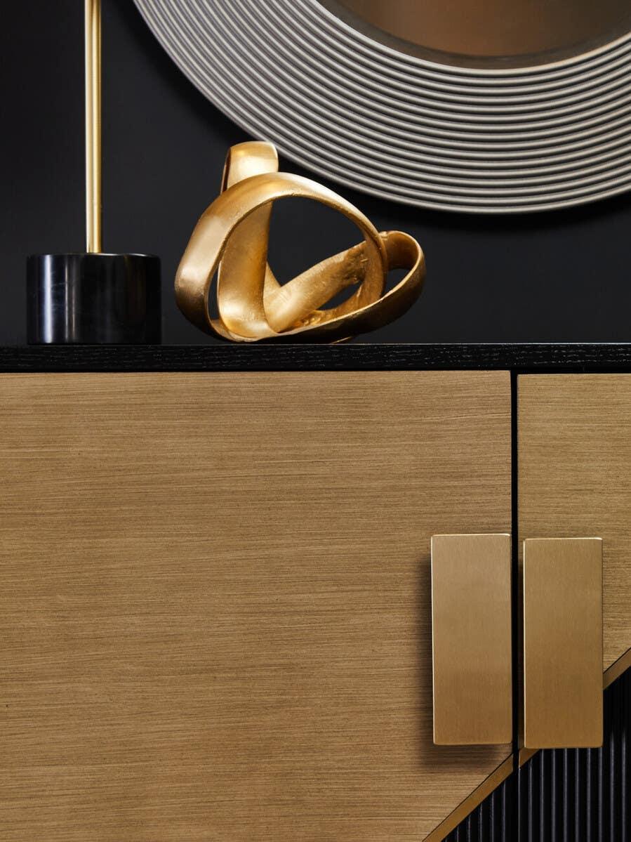 Oak sideboard with gold handles, abstract gold sculpture, and round textured wall mirror