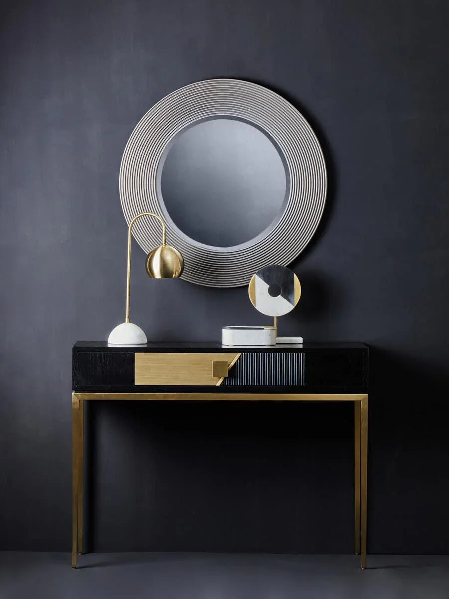 Modern hallway console table with gold accents and round wall mirror on dark background