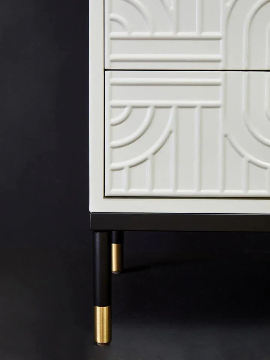 White geometric pattern chest of drawers with black and gold legs, close-up view