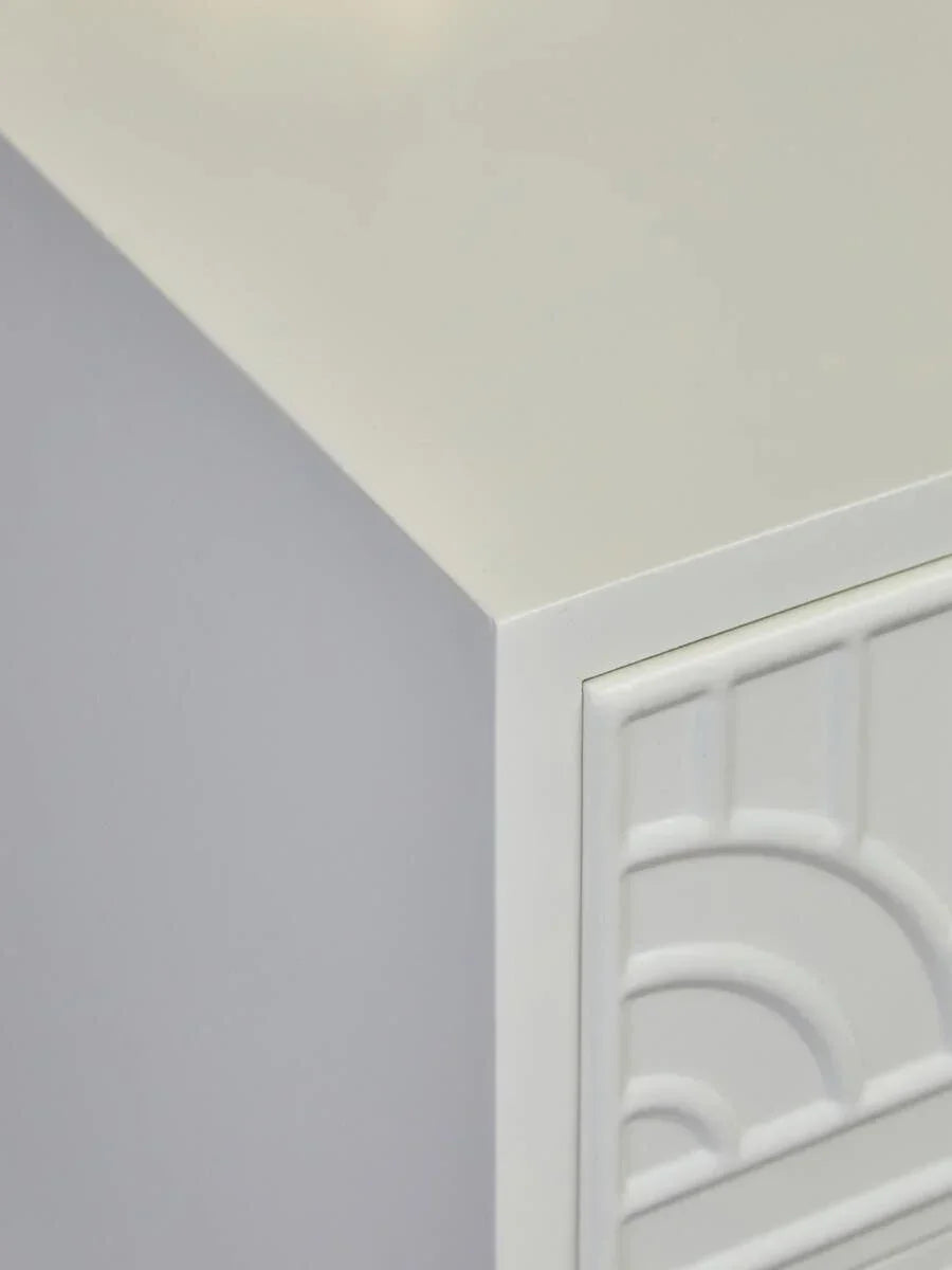 White wooden cabinet corner with embossed geometric drawer front detail