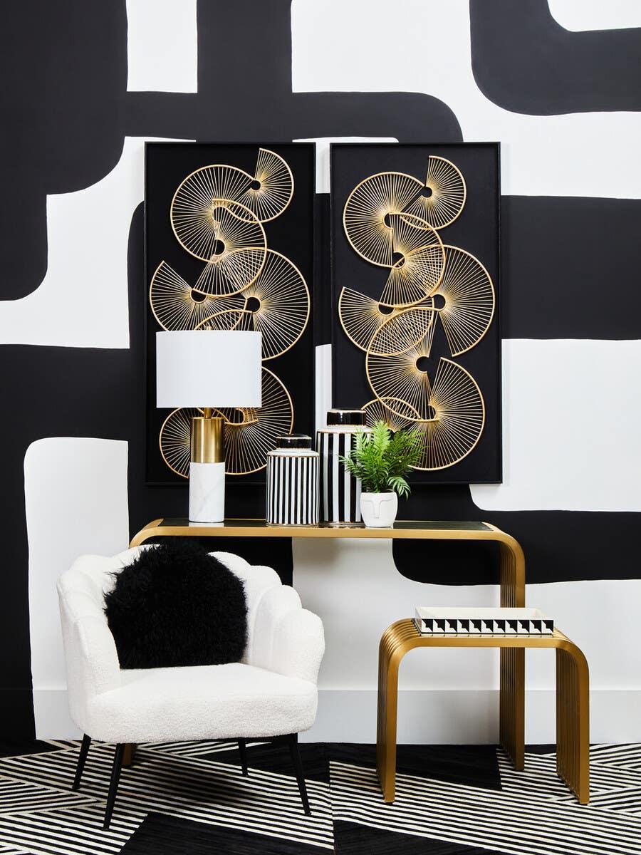 Modern gold console table with black and white decor, white accent chair, abstract wall art