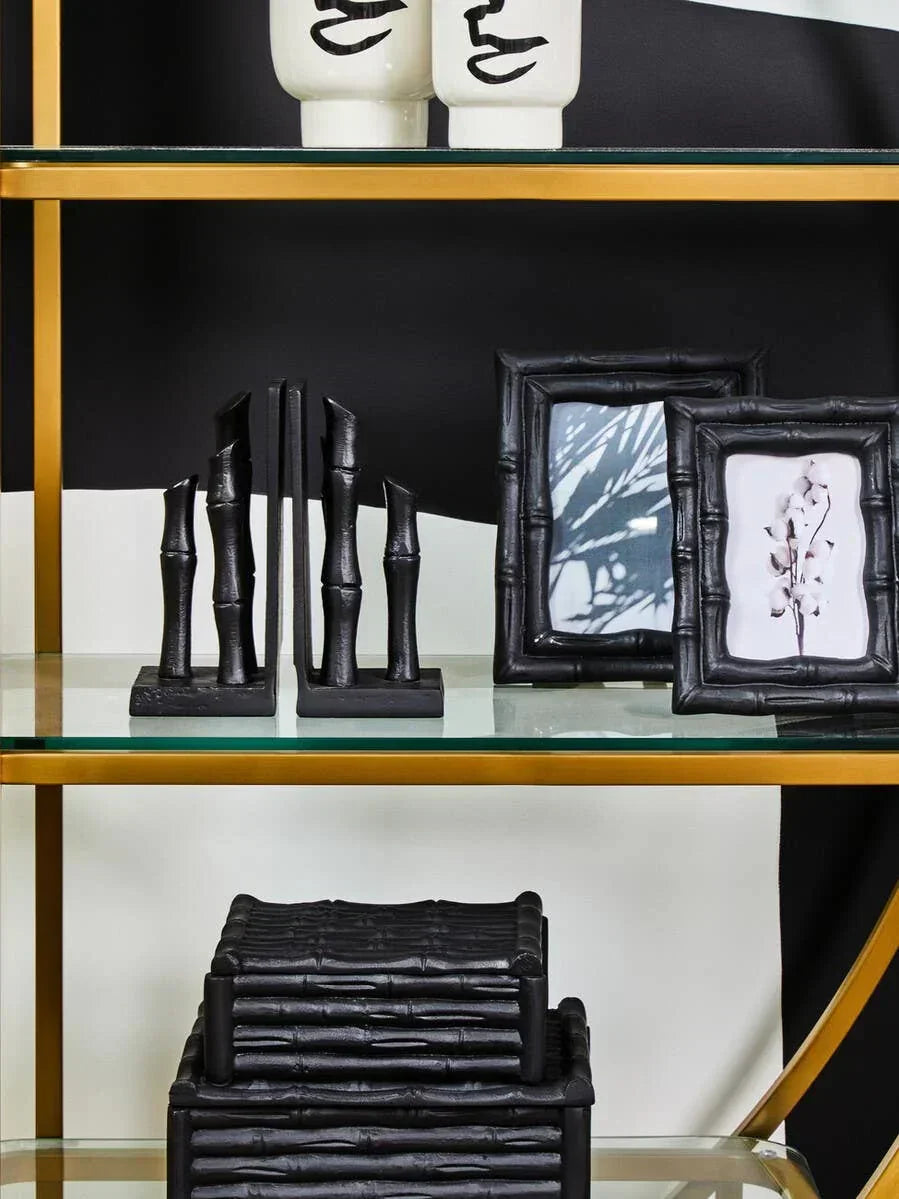Black bamboo effect home decor accessories on glass and gold shelving unit