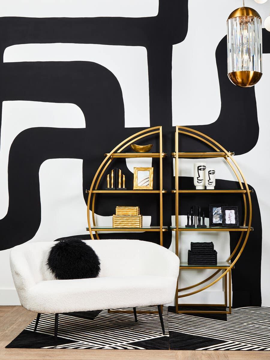 White boucle sofa with black cushion, gold round shelving unit, geometric rug, modern decor