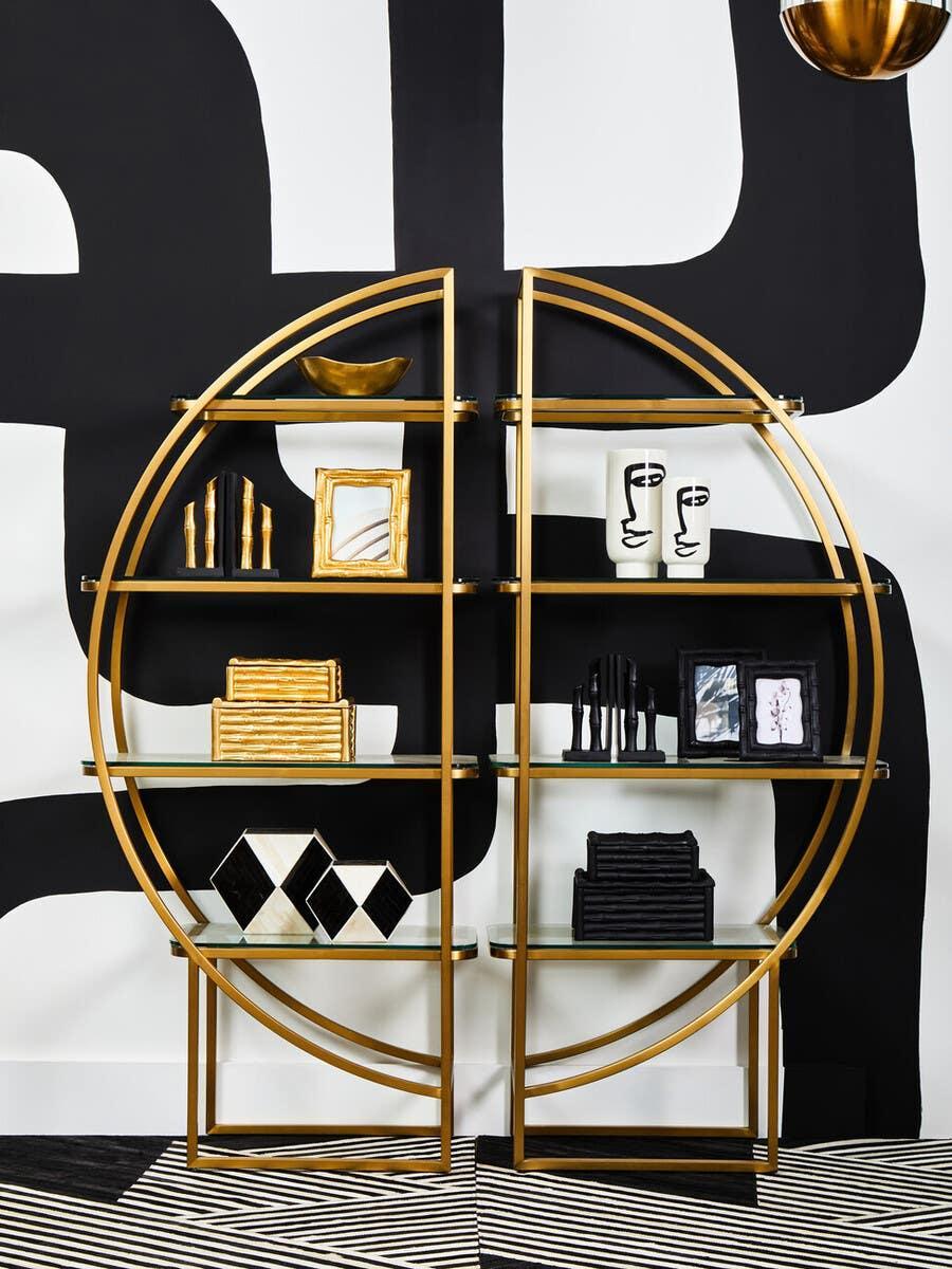 Gold circular display shelf with glass shelves holding decorative ornaments and books