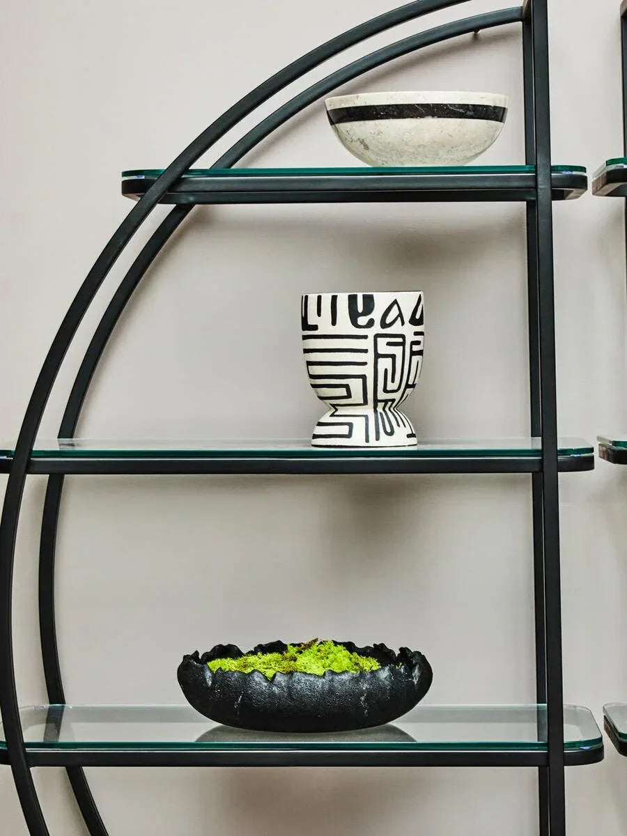 Modern glass and metal shelving unit with decorative ceramic bowls and planter