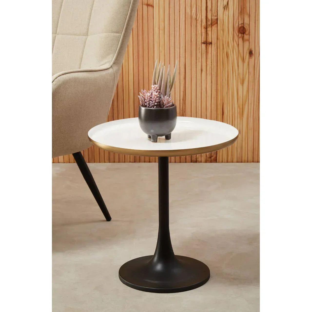 Modern round side table with white top, black pedestal base, small plant on surface