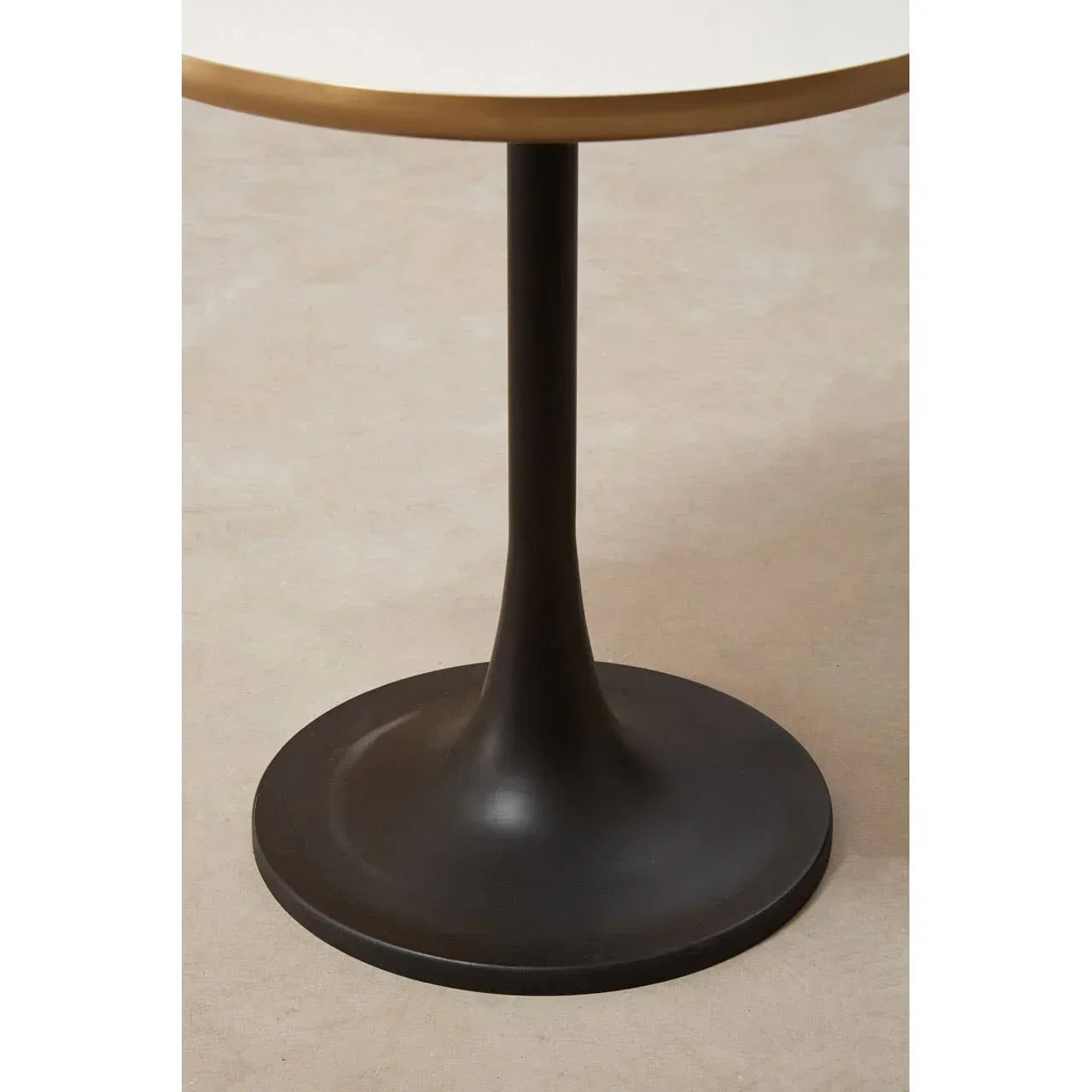 Round dining table with black pedestal base and white tabletop, side angle view