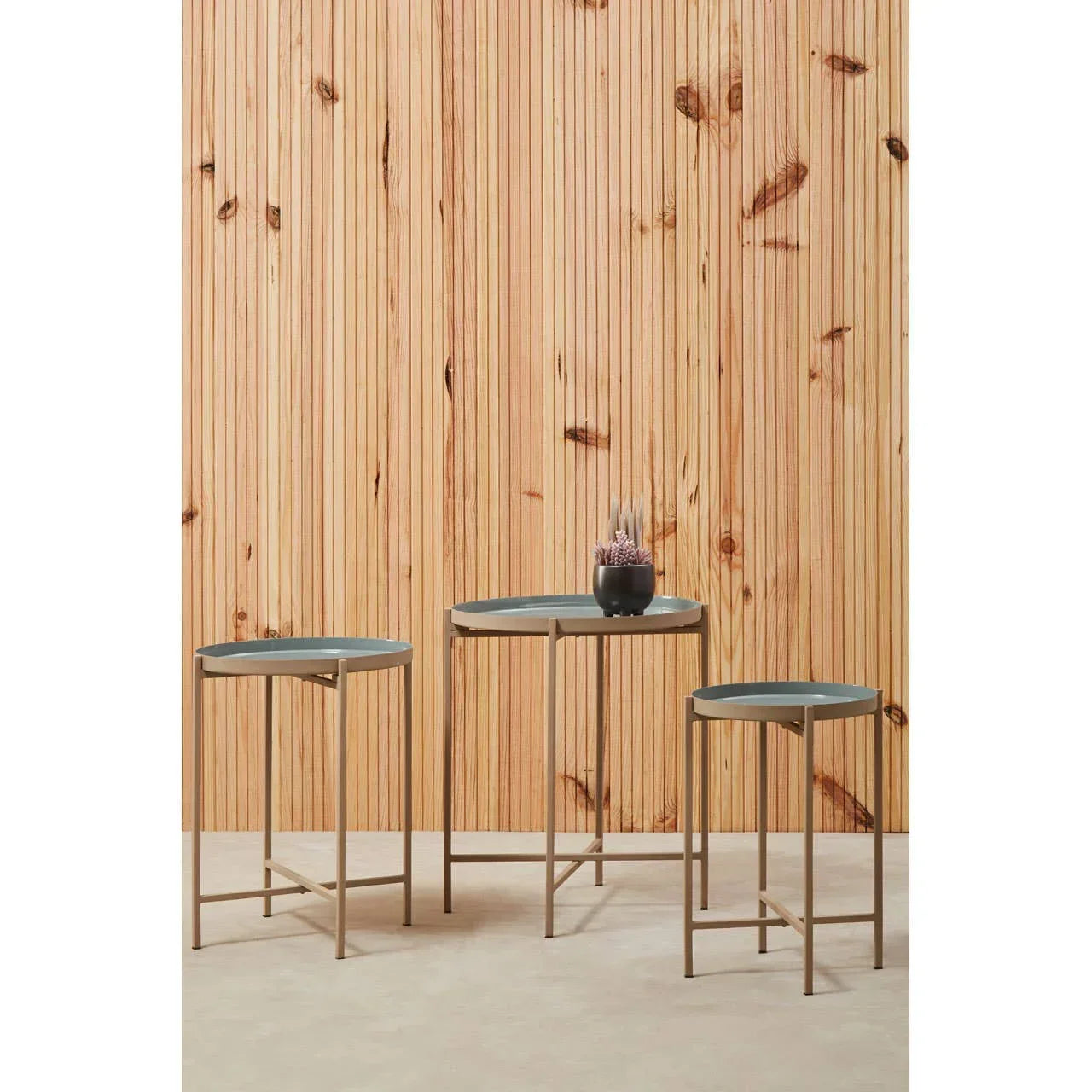 Set of three round metal nesting tables with grey tops and gold frames, indoor setting