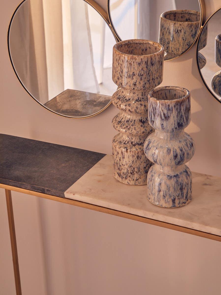 Ceramic decorative vases with blue texture on marble console table beside round wall mirrors