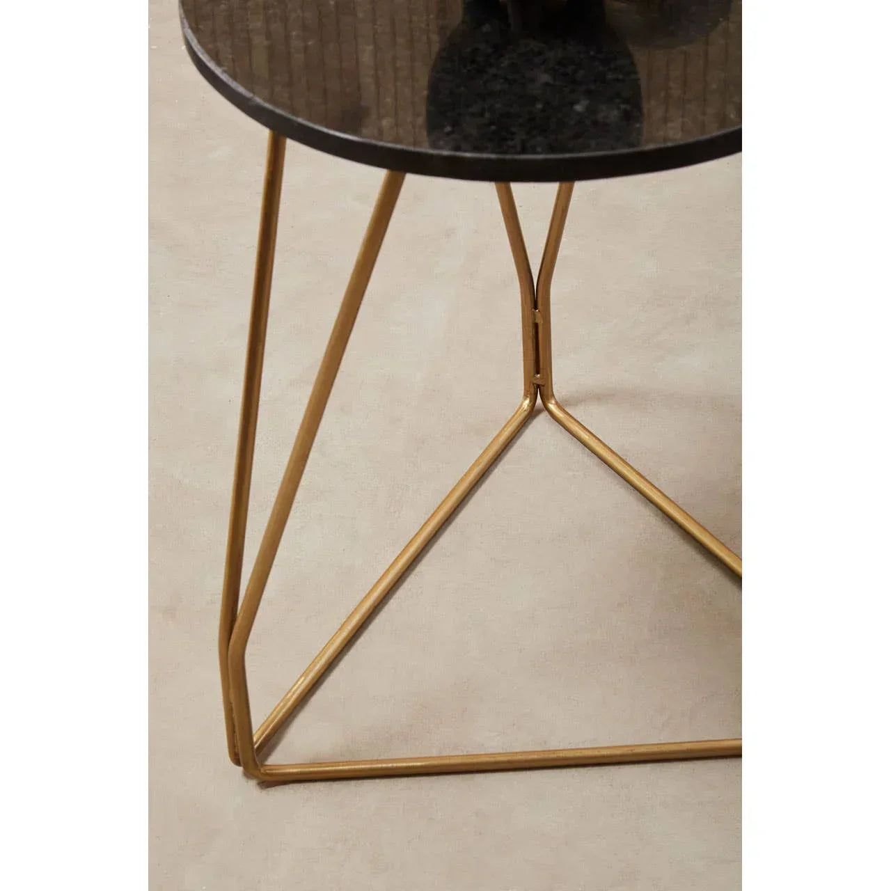Round black glass top side table with gold metal frame, angled leg detail visible