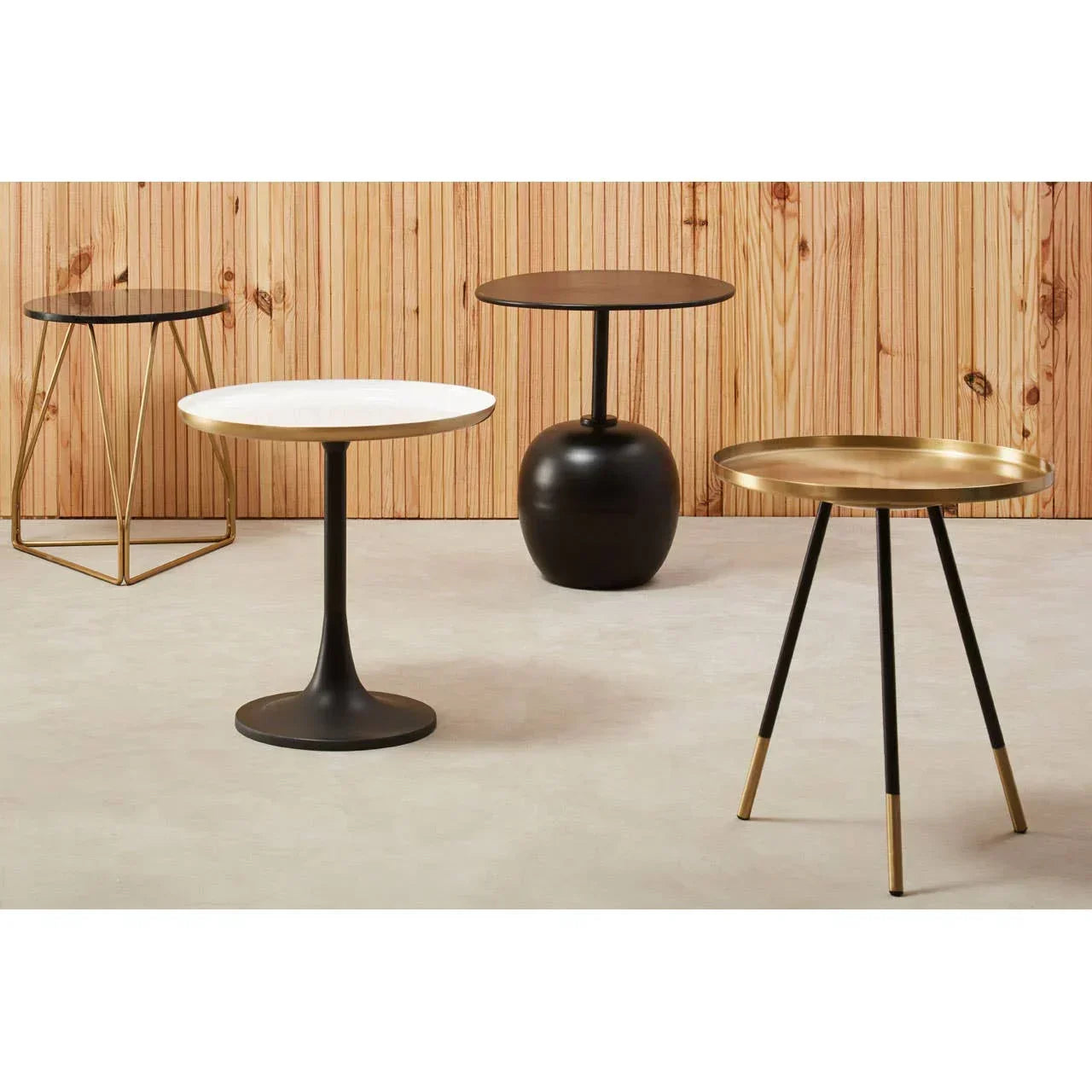 Modern side tables set with black, white, and gold finishes on neutral flooring
