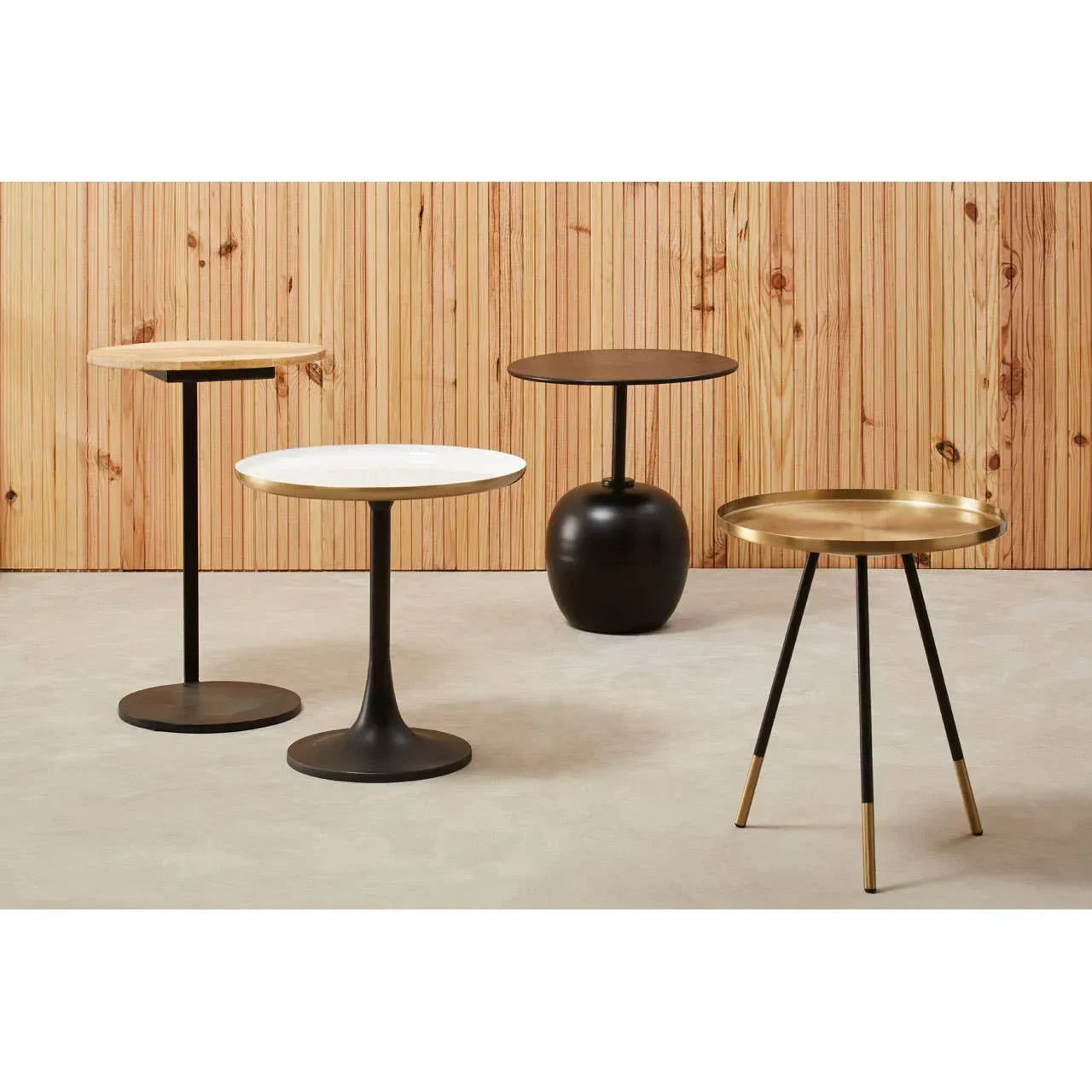 Modern accent tables in black, white, wood, and gold finishes on light floor
