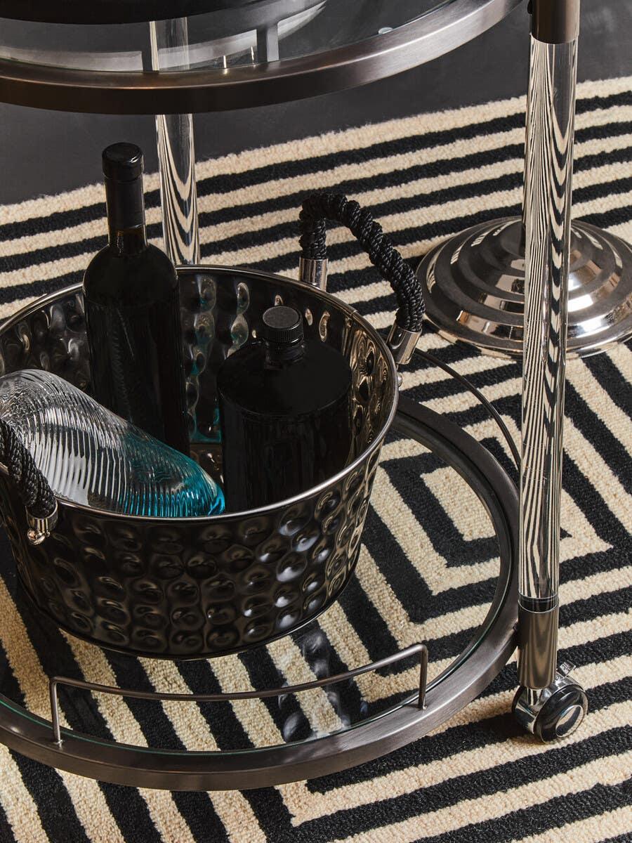 Modern metal drinks trolley with glass shelves on black and cream geometric rug