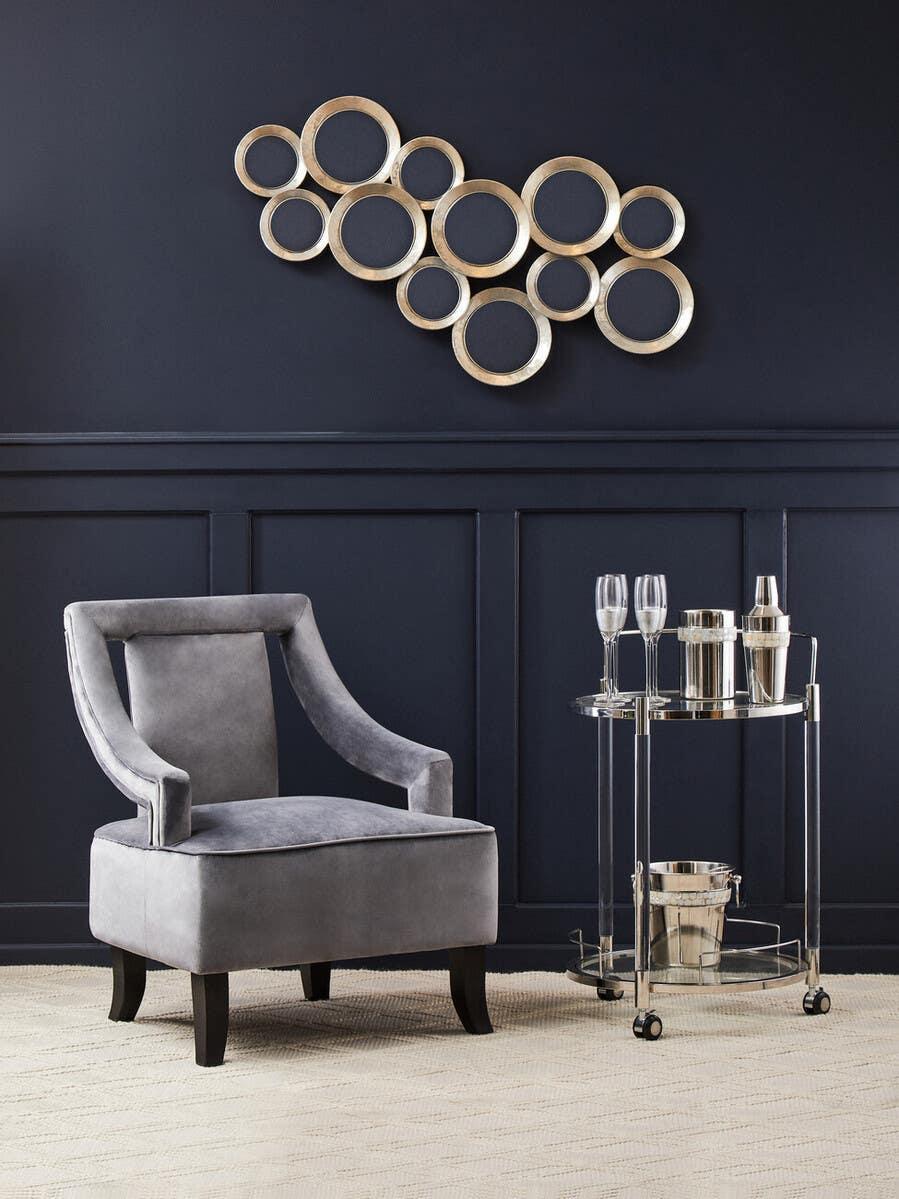 Grey velvet accent chair beside chrome drinks trolley on cream textured rug
