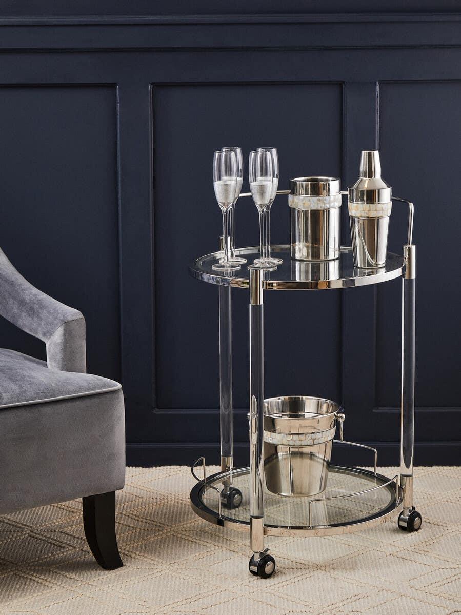 Chrome drinks trolley with glass shelves, champagne flutes, ice bucket and cocktail shaker