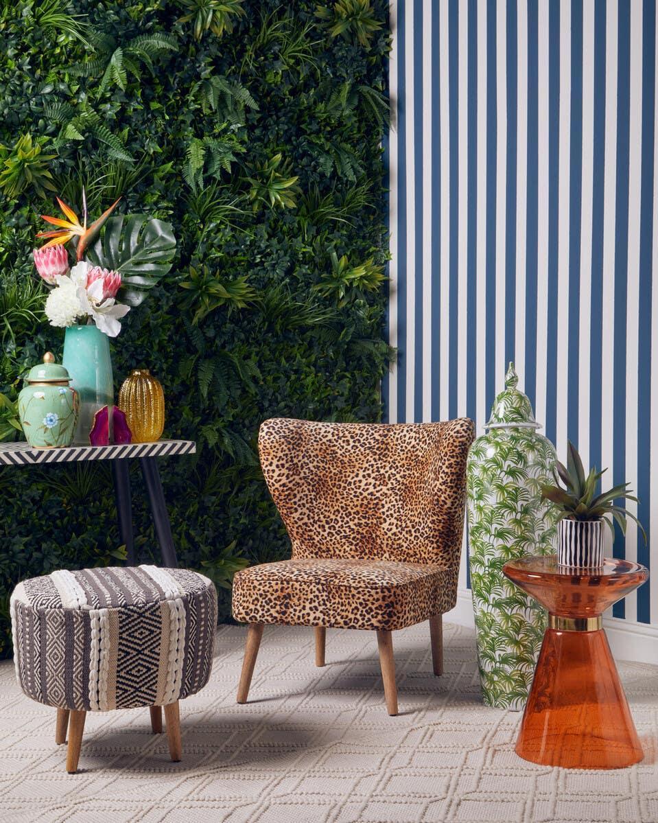 Leopard print accent chair with patterned footstool and orange side table in modern living room