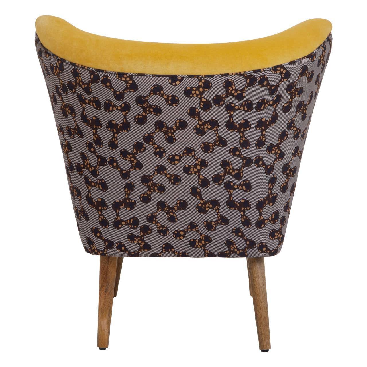 Patterned accent chair with yellow velvet trim and wooden legs, rear angle view
