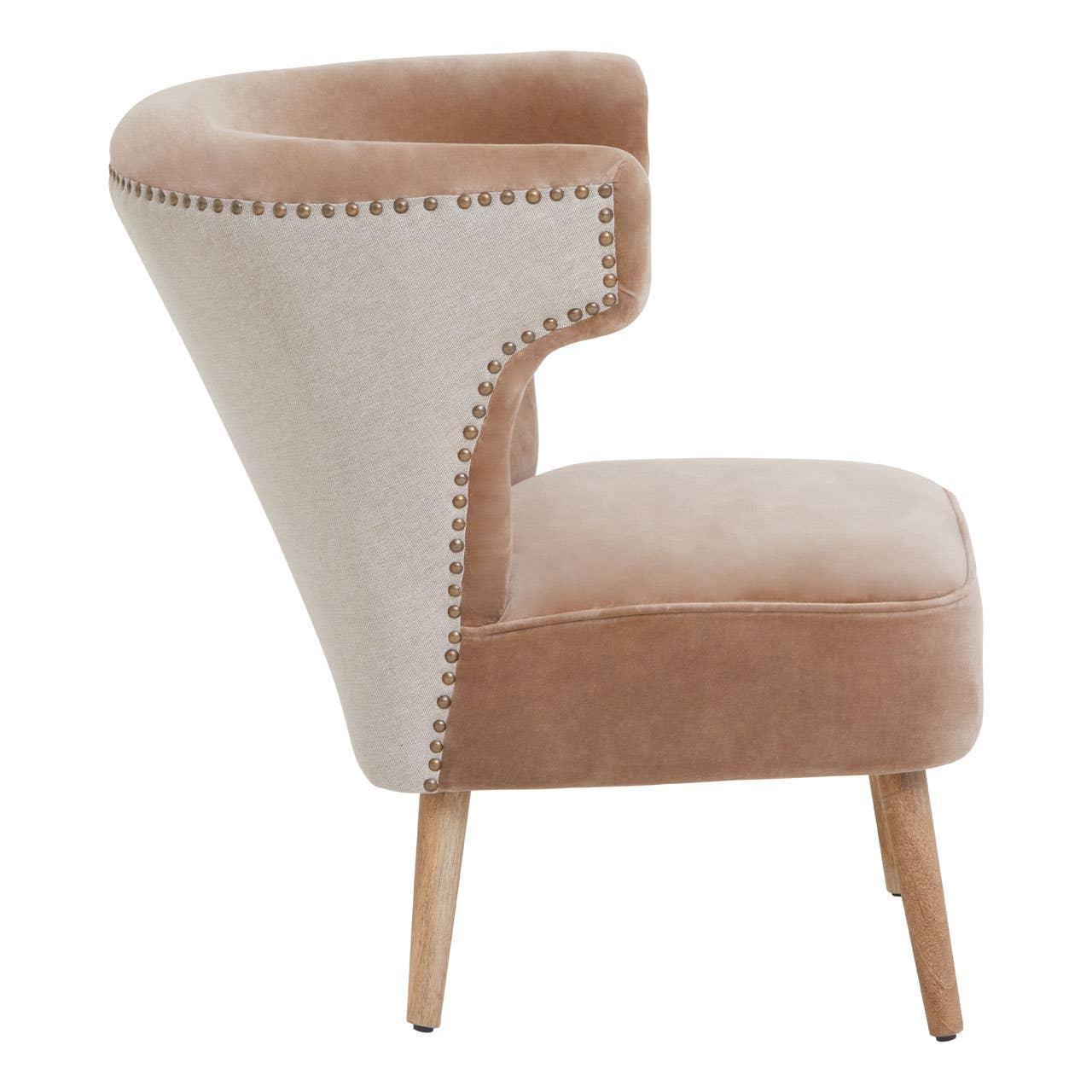 Beige velvet accent chair with studded trim and wooden legs, side profile view
