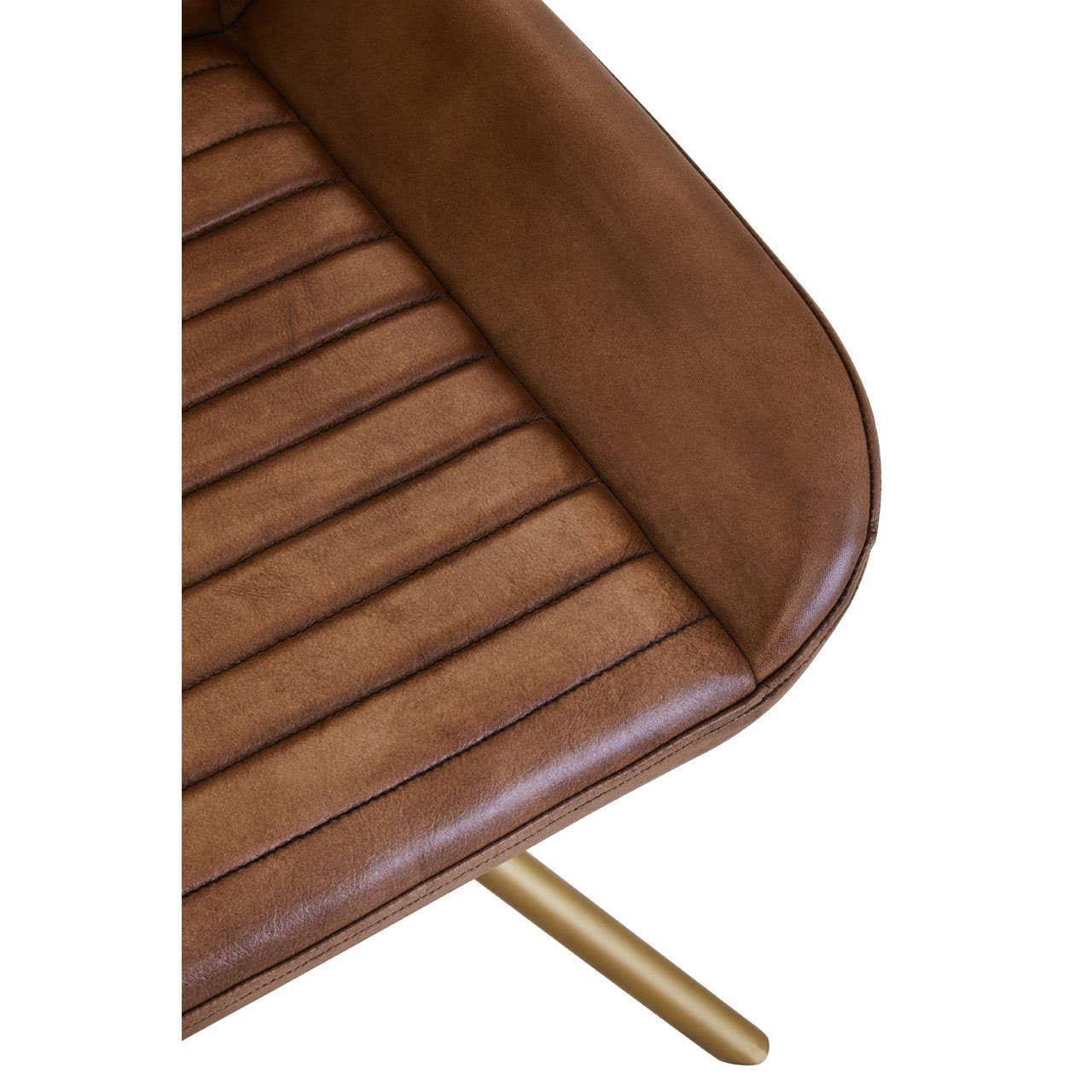 Close-up of brown leather dining chair seat with stitched detail and gold metal leg