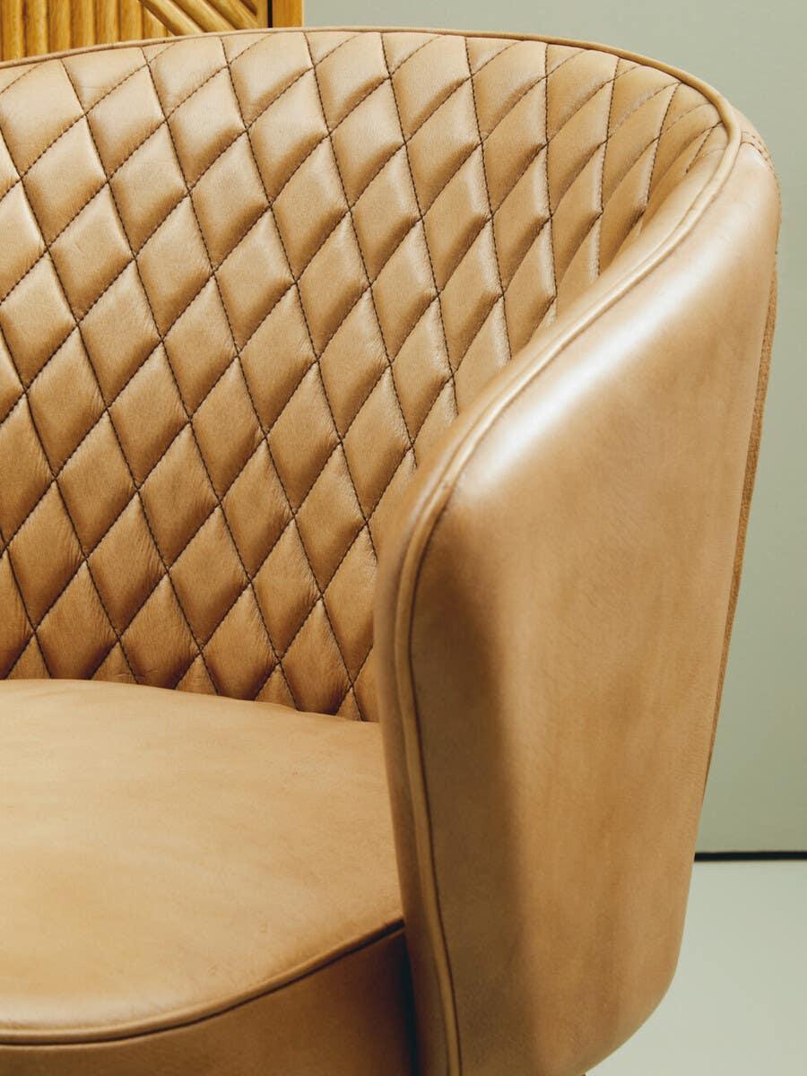 Tan leather armchair with diamond quilted backrest and curved arm design