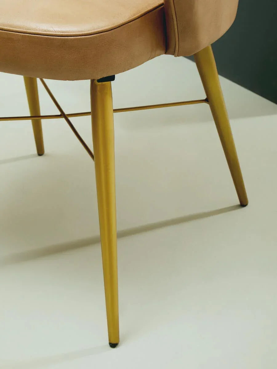 Tan leather chair with slim gold metal legs, close-up on upholstery and modern frame
