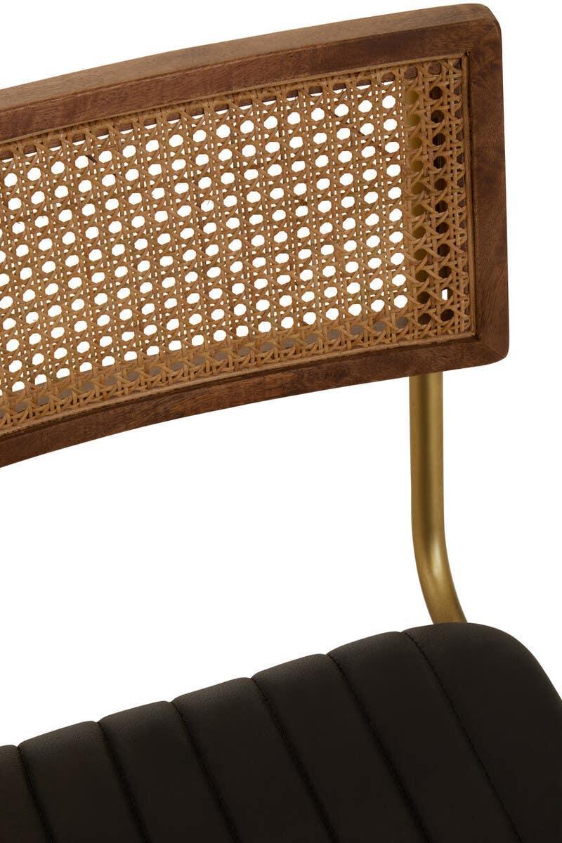 Close up of rattan back dining chair with brass leg and black upholstered seat