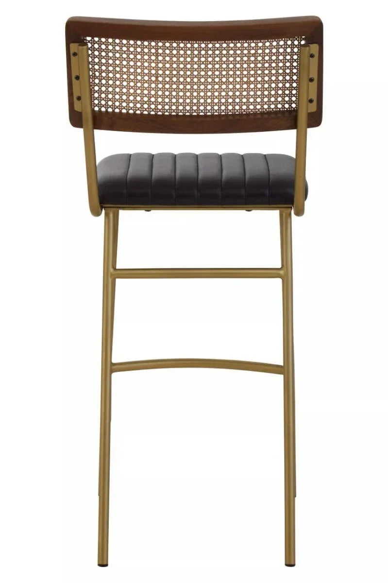 Bar stool with gold metal legs, black ribbed seat, and cane backrest in wood frame, rear view