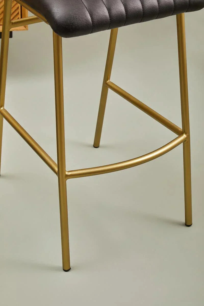 Black faux leather bar stool with gold metal legs, close-up on seat and base