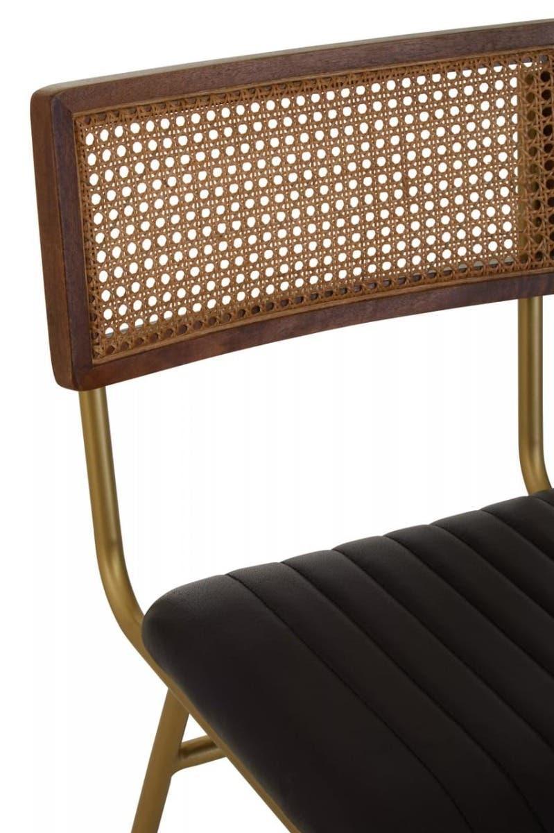 Rattan dining chair with black padded seat and gold metal frame, close-up view