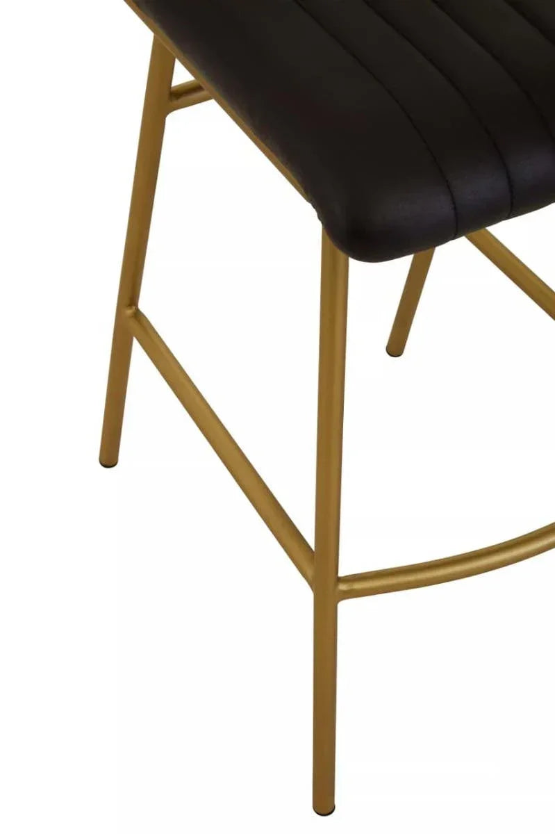 Black leather bar stool seat with gold metal legs, close-up side view