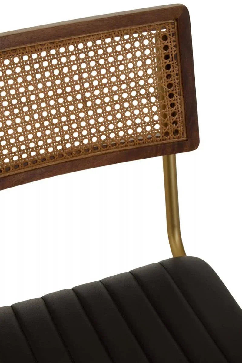 Dining chair with black padded seat, rattan backrest and gold metal legs closeup