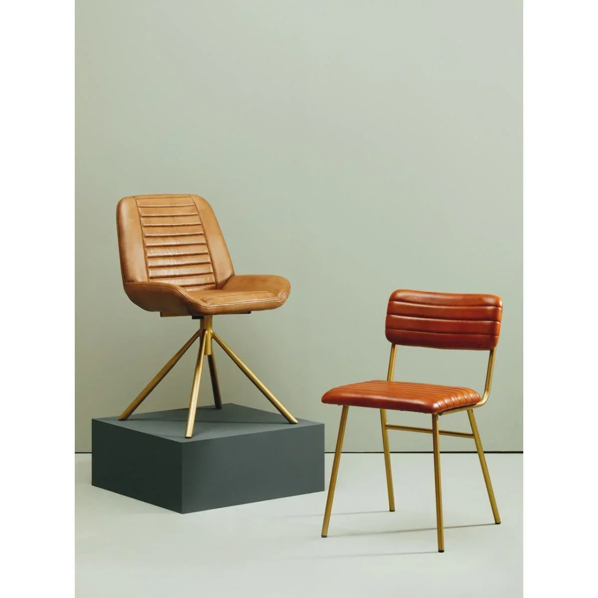 Tan leather dining chairs with gold metal legs, one swivel chair and one standard chair