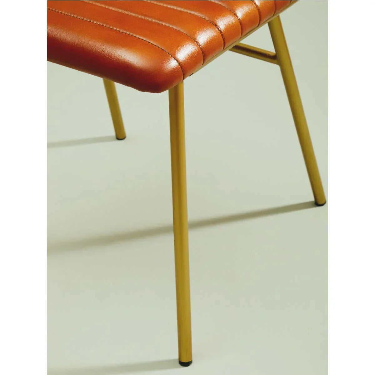 Brown leather dining chair seat with vertical stitching and gold metal legs