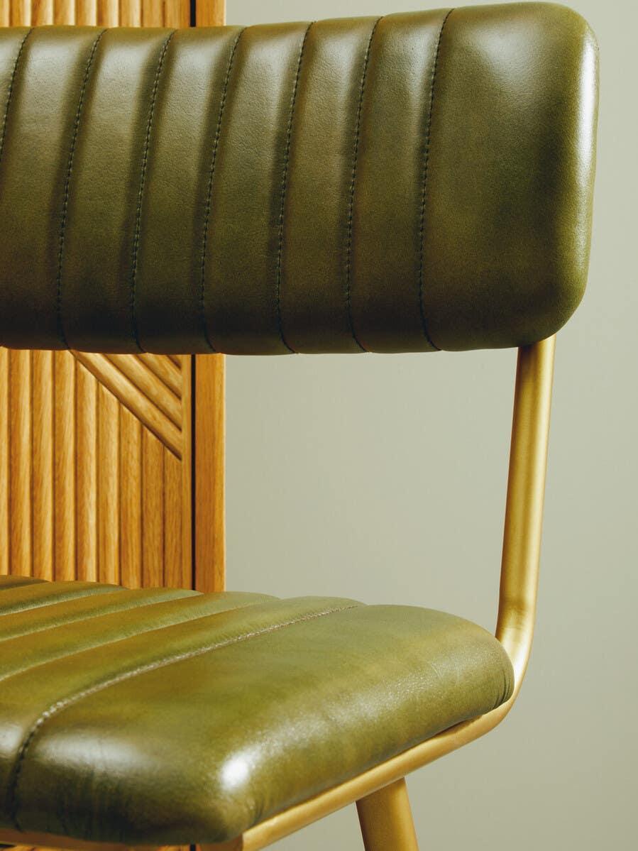 Green leather dining chair with gold frame and vertical stitching detail