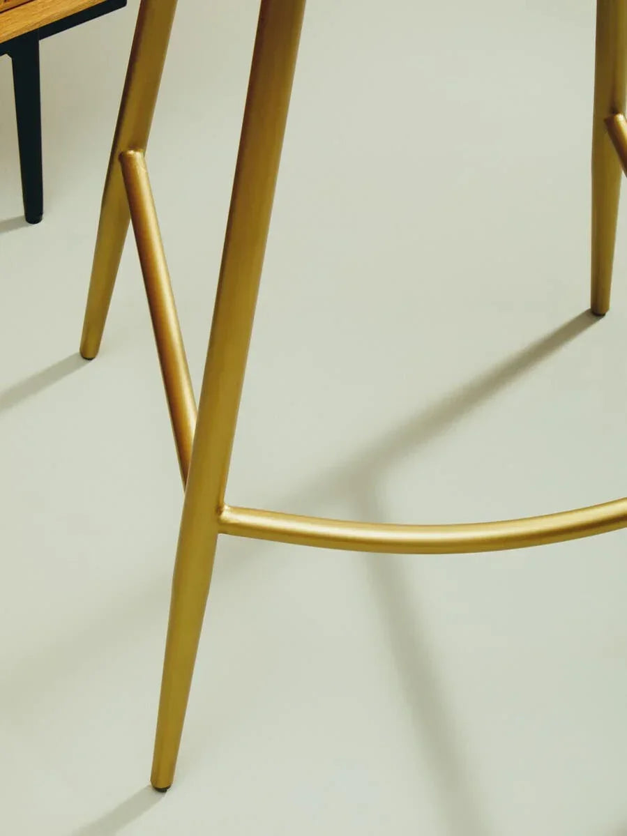 Gold metal bar stool legs with curved footrest on light floor