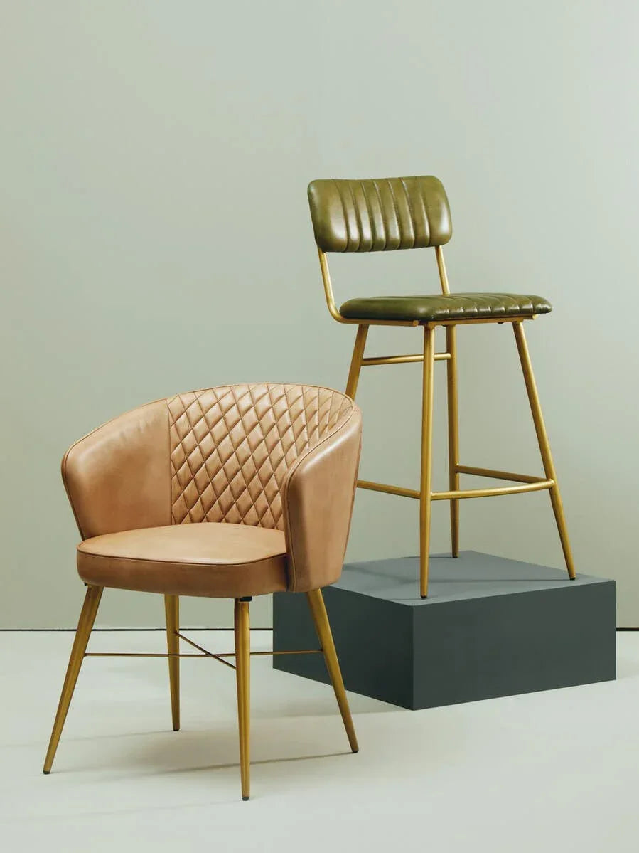Tan quilted armchair and green bar stool with gold legs against neutral background
