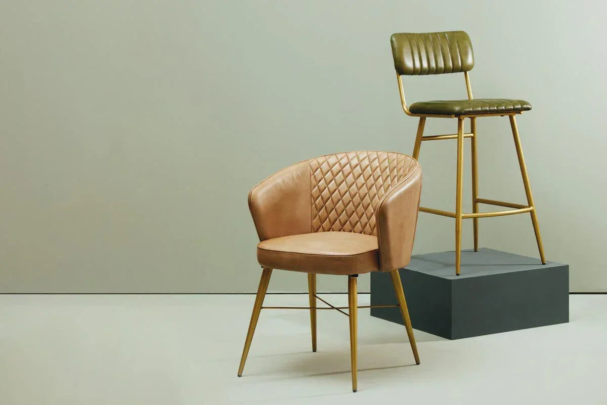 Tan quilted accent chair and green bar stool with gold legs on neutral background