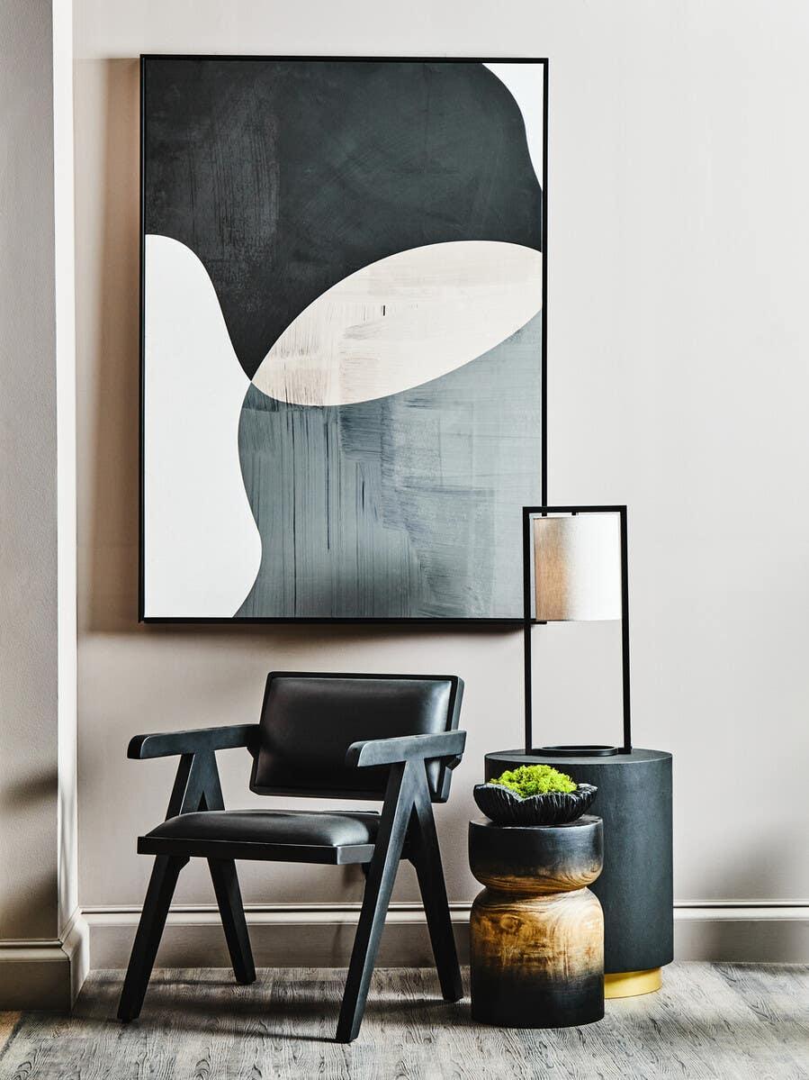Modern black accent chair with side tables, lamp and abstract wall art in living room