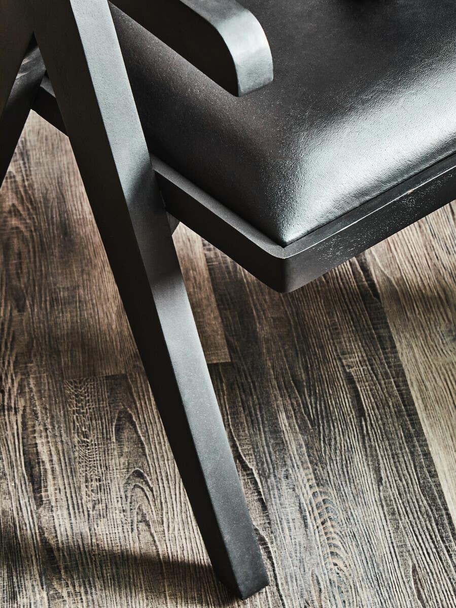 Modern black dining chair with faux leather seat and angled wooden legs on wood floor