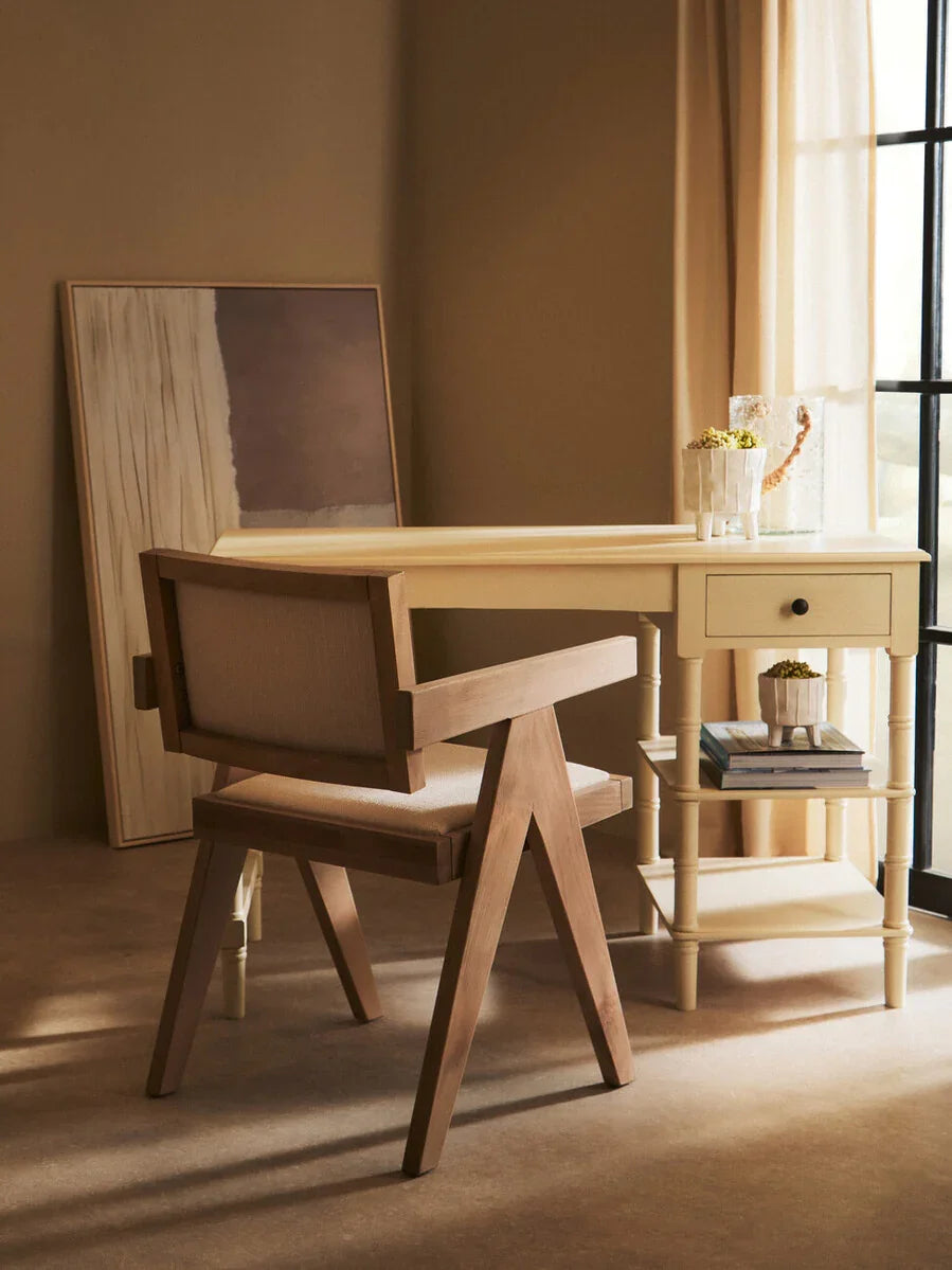 Wooden accent chair with beige upholstery beside cream writing desk in sunlit room